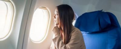 Woman seated on a plane looking out a window.